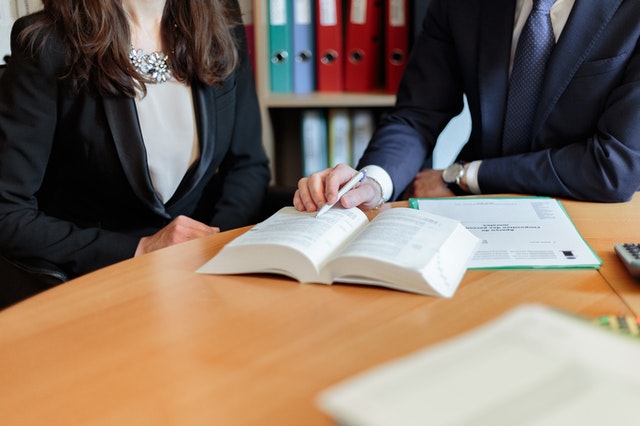 two people in a law office seated at a table looking at a legal book